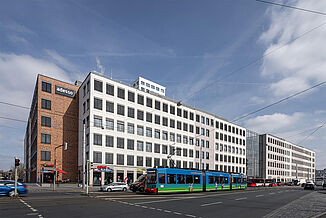 Widok na dzielnicę miejską Seetor City Campus w Norymberdze z tramwajem przed budynkiem.