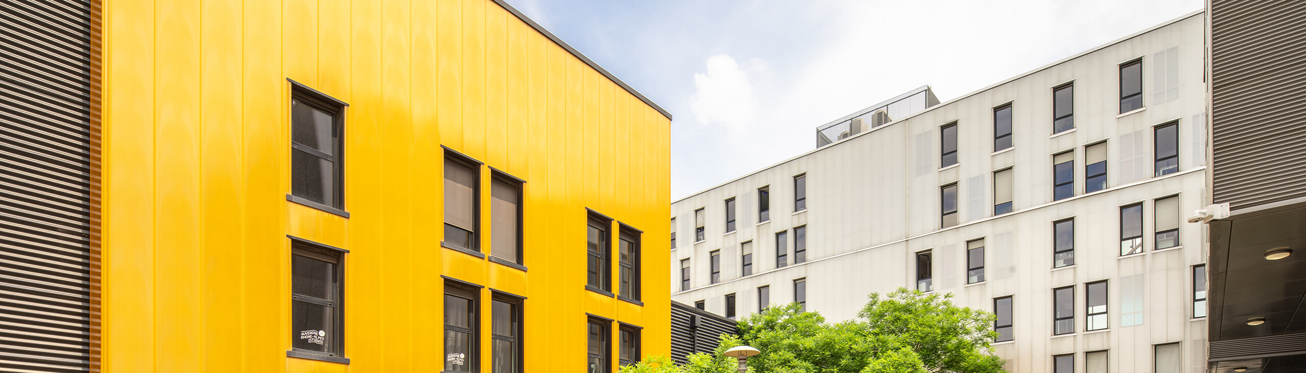 Yellow and grey façade with windows of the Pôle PIXEL office and commercial building in France.